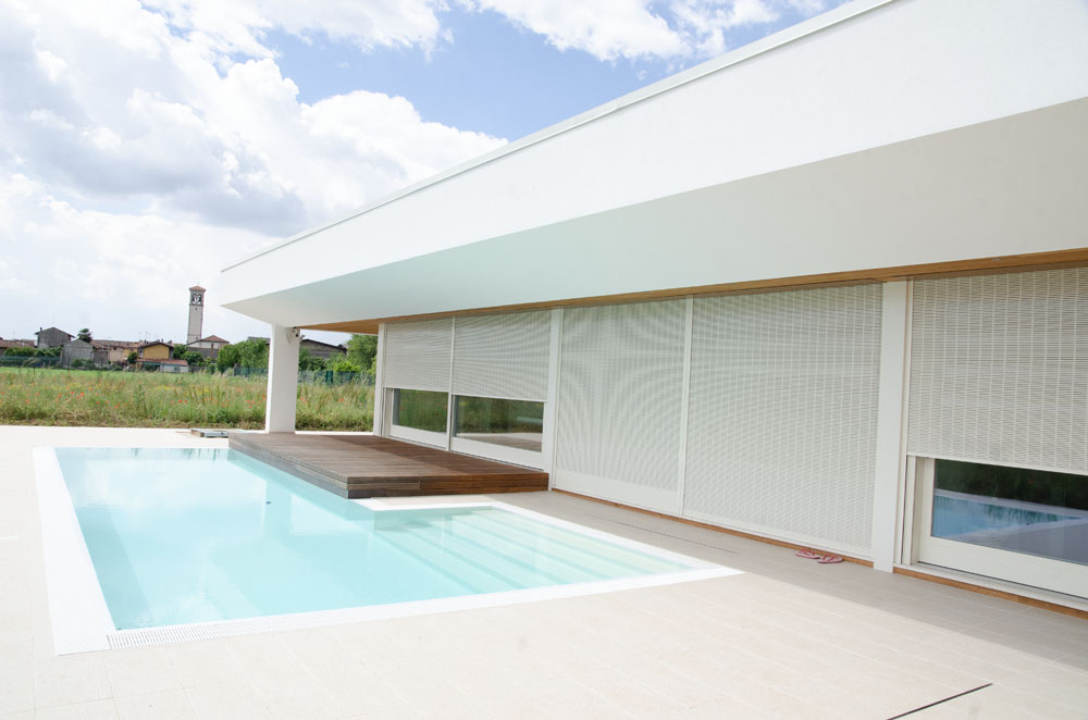 Hiša z bazenom, bela avtomatska senčila na panoramski steni.