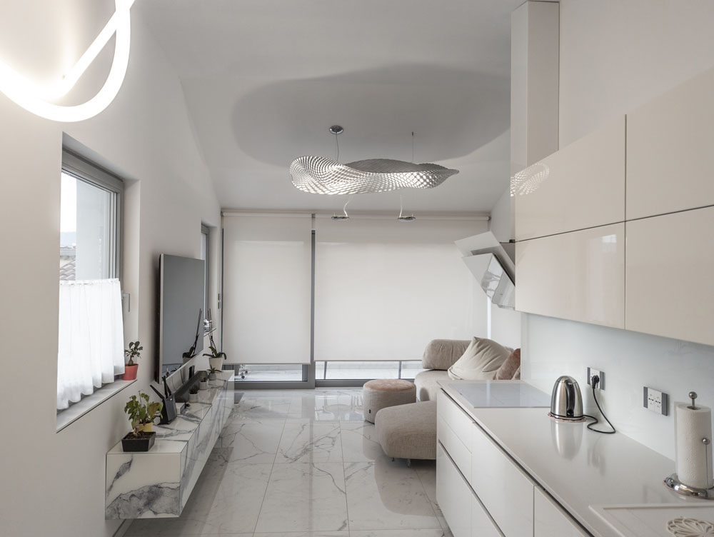 Dnevni prostor in kuhinja v beli barvi.